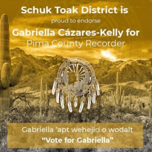 Image Description A yellow tinted photo of mountainous desert with the following text written in white: Schuk Toak District is proud to endorse Gabriella Cázares-Kelly for Pima County Recorder. Gabriella ‘apt wehejid o wodalt! “Vote for Gabriella!” A District Logo is in the center of the graphic. It is a Man in the Maze Symbol, with a cut out of the Schuk Toak District Boundaries, The text: Schuk Toak District, Tohono O’odham Nation and the names of the communities of Schuk Toak: San Isidro, San Pedro, Comobabi, Queen’s Well, Santa Rosa Ranch, Sil Nakya, Fresnal, Garcia Strip and Pan Tak are incorporated into the seal. Nine feathers hang from the bottom of the seal to represent the 9 communities.