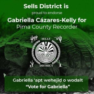 Image Description: Green graphic with a turtle background and the following text: Sells District is proud to endorse Gabriella Cázares-Kelly for Pima County Recorder Gabriella ‘apt wehejid o wodalt. “Vote for Gabriella” The Sells District Seal is centered in the document. The seal shows dancers surrounding the Man in the Maze symbol. There are cactus, mountains, and people harvesting bahidaj (saguaro fruit) in each of the 4 corners. The text: North Communities, Ge Oidag, Sells and Kawulk overlay the maze.